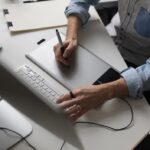 Intelligenza artigiana, diffusione competenze AI Artigiano Digitale -Designer hands using graphics tablet while working with computer at studio or office. (fonte: Magnific Licenziata)